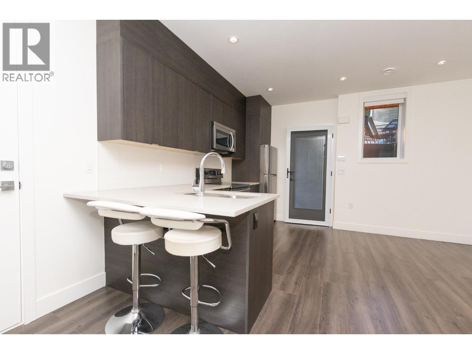 A modern kitchen with a bar stool and a fridge.