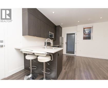 A modern kitchen with a bar stool and a fridge.