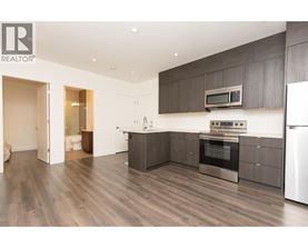 A modern kitchen with dark wood floors and stainless steel appliances.
