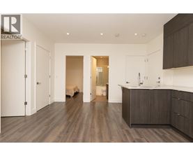 A modern kitchen with dark wood floors and white walls.