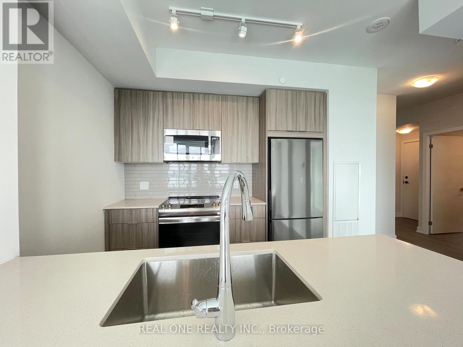 A modern kitchen with a stainless steel sink and refrigerator.