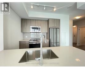 A modern kitchen with a stainless steel sink and refrigerator.