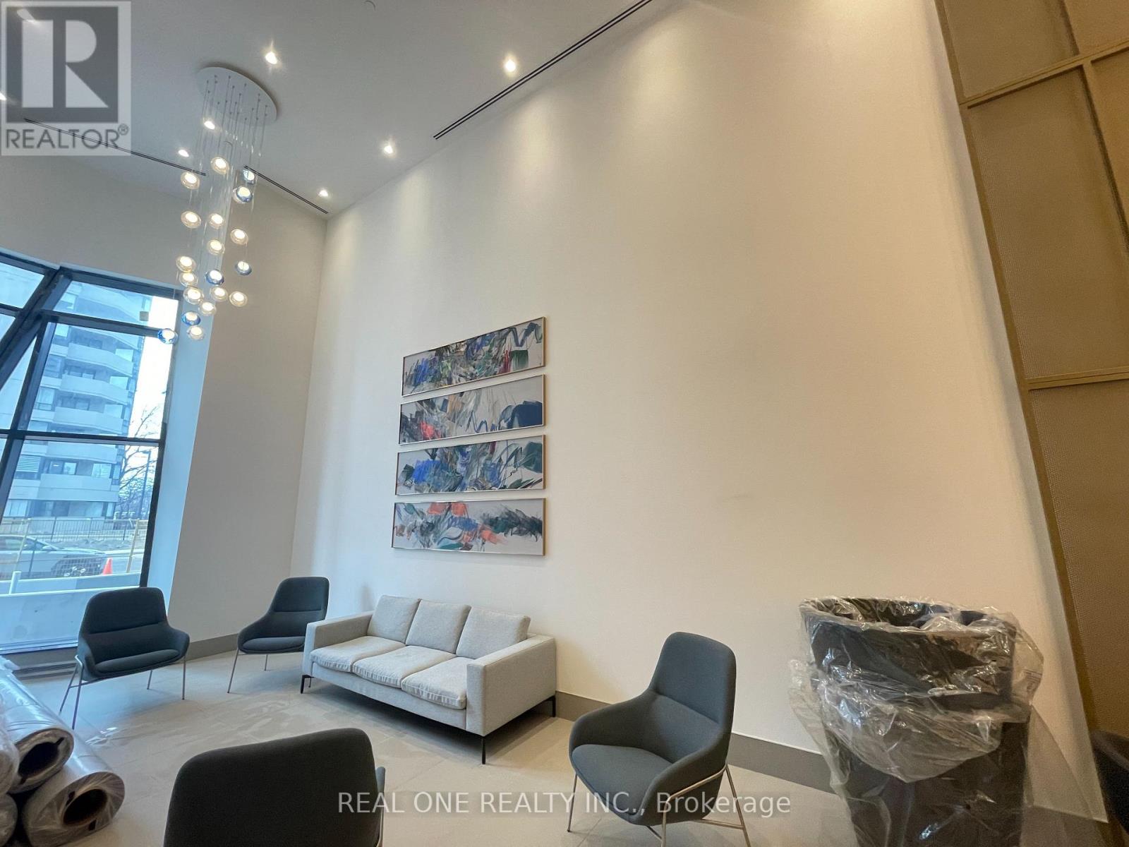 A realtor's office with a white couch, black chairs, and a large painting on the wall.