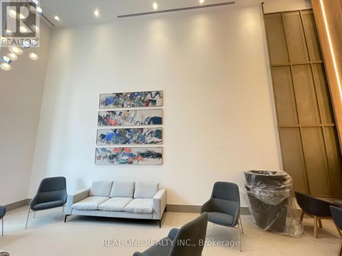 A living room with a grey sofa, a black chair and a painting on the wall.