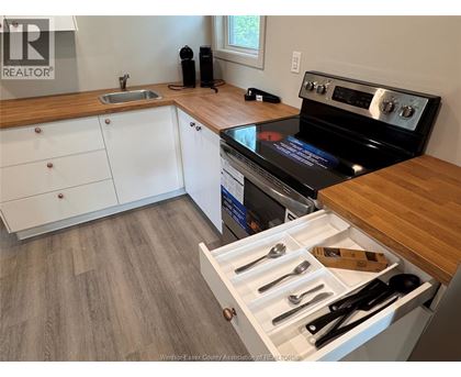 A kitchen with a stove top oven and a drawer of utensils.