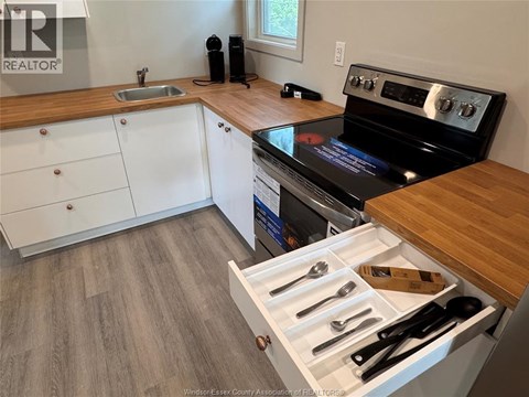A kitchen with a stove top oven and a drawer of utensils.