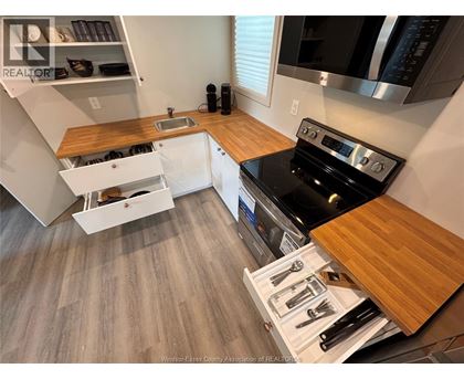 A kitchen with a black stove top oven and wooden countertops.