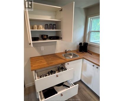 A kitchen with white cabinets and a wooden counter top.