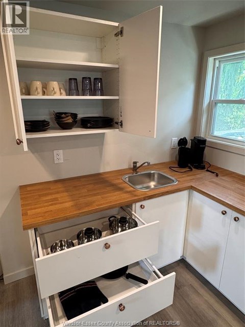A kitchen with white cabinets and a wooden counter top.