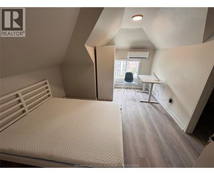 A bedroom with a bed, desk, and chair.
