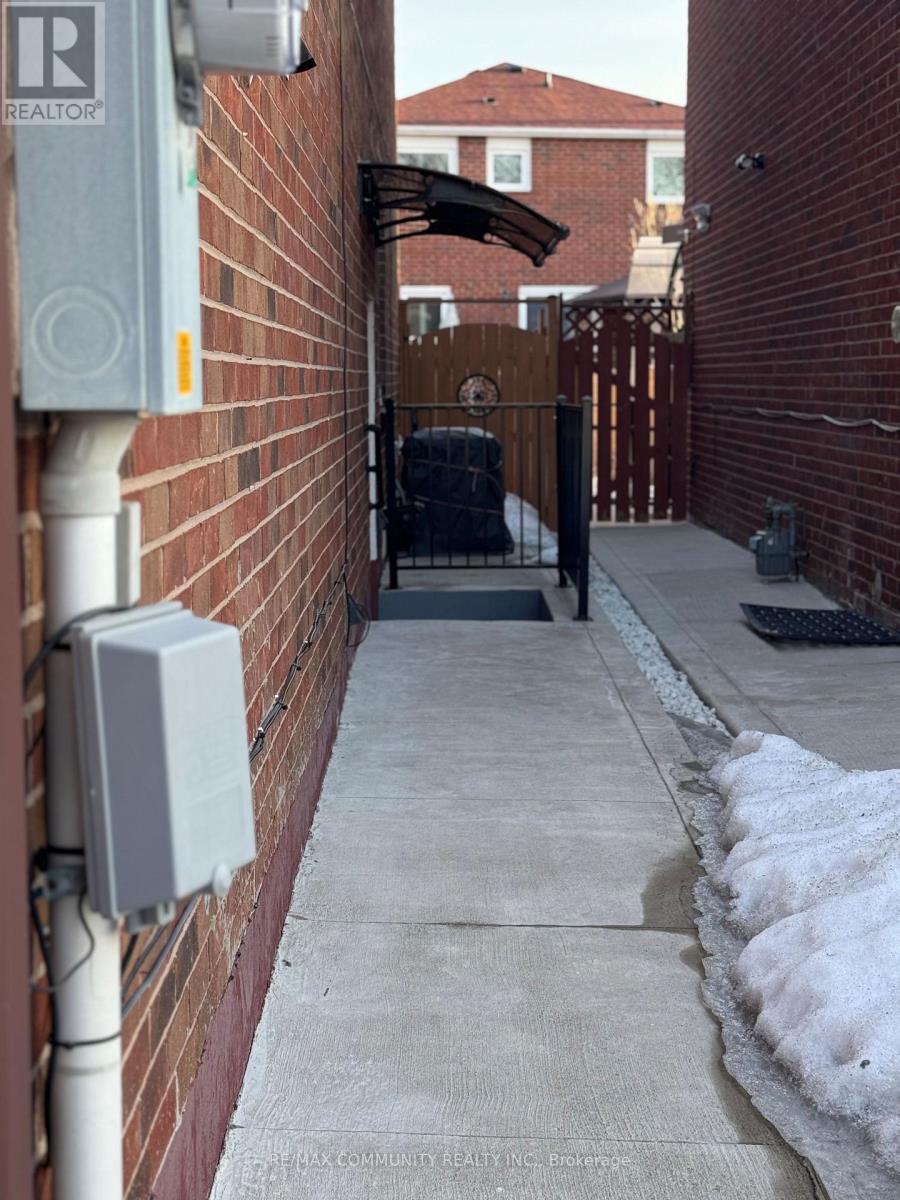 A white electrical box is mounted on a red brick wall.
