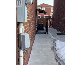 A white electrical box is mounted on a red brick wall.