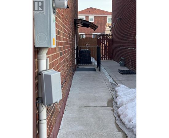 A white electrical box is mounted on a red brick wall.