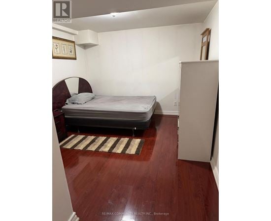 A bedroom with a bed, a chair, and a rug.
