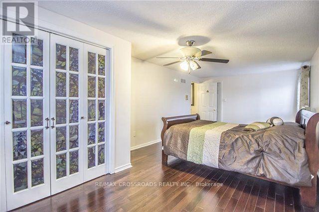 A bedroom with a bed, a ceiling fan, and a glass door.