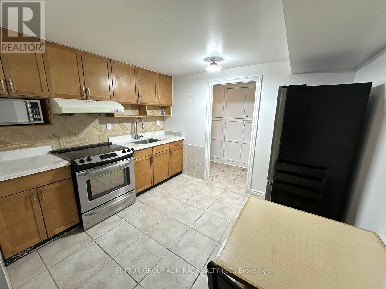 A kitchen with wooden cabinets and a black refrigerator.