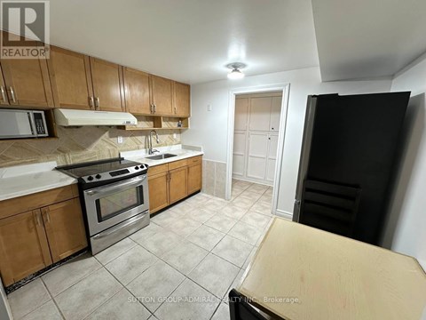 A kitchen with wooden cabinets and a black refrigerator.