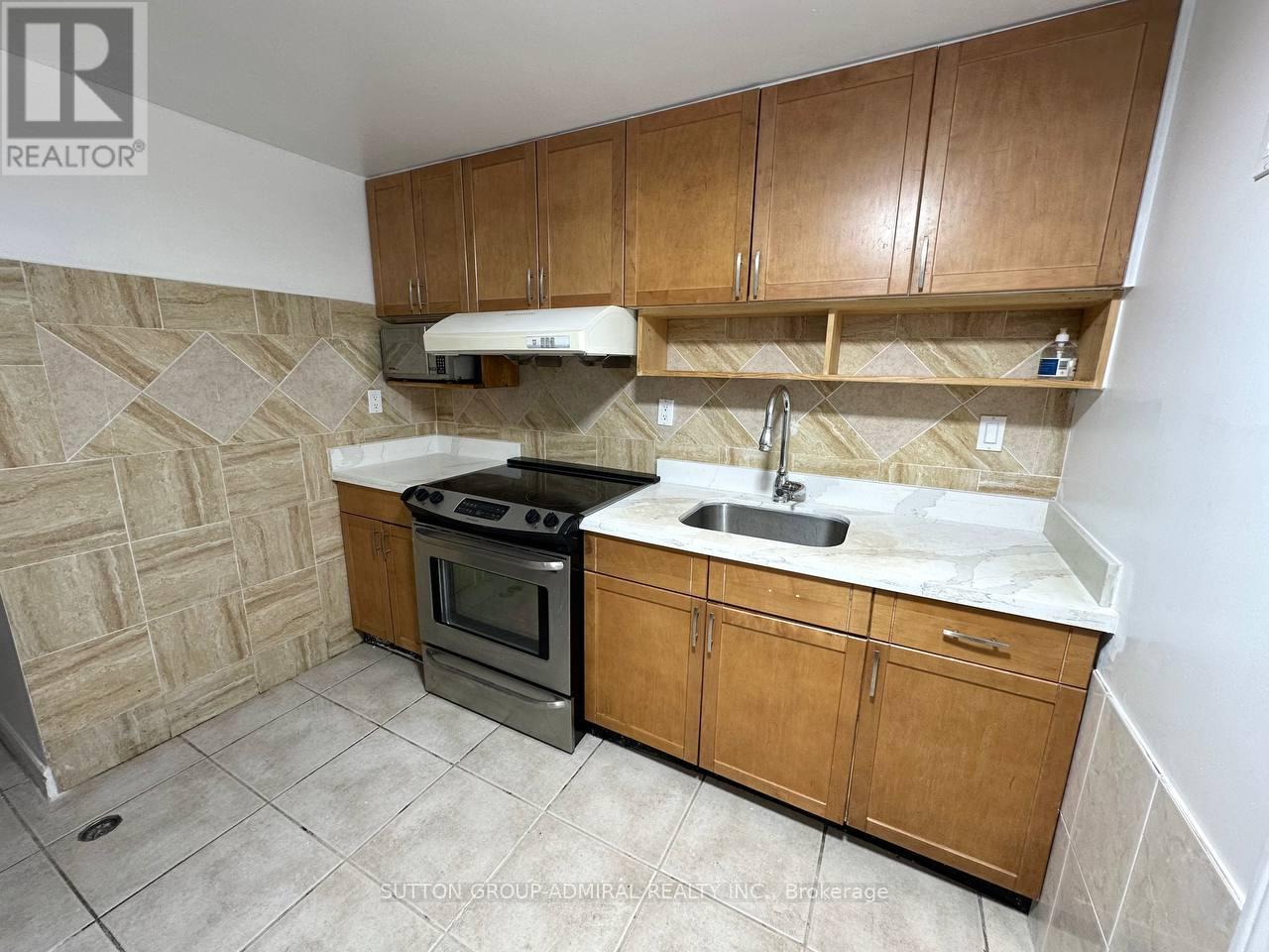 A kitchen with wooden cabinets and a tiled floor.