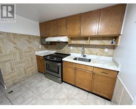 A kitchen with wooden cabinets and a tiled floor.