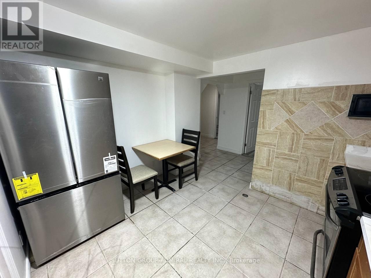 A kitchen with a refrigerator, table and chairs.