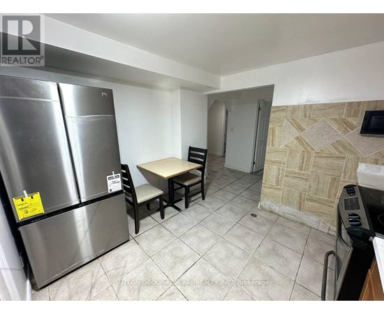 A kitchen with a refrigerator, table and chairs.