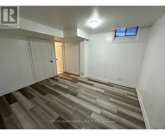 A room with wooden flooring and a window with a white frame.