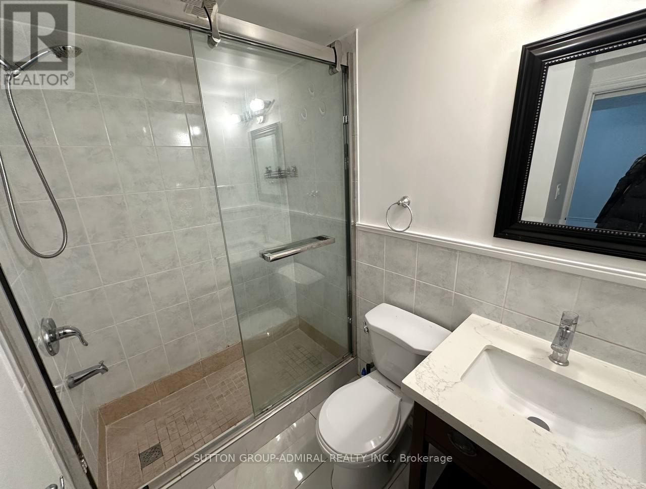 A bathroom with a toilet, sink, and glass shower stall.