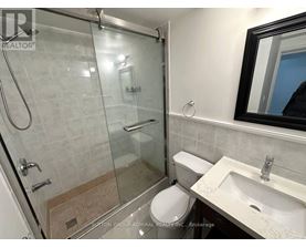 A bathroom with a toilet, sink, and glass shower stall.