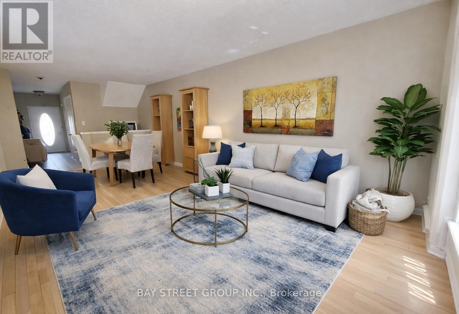 A living room with a white couch, blue chairs, and a painting on the wall.