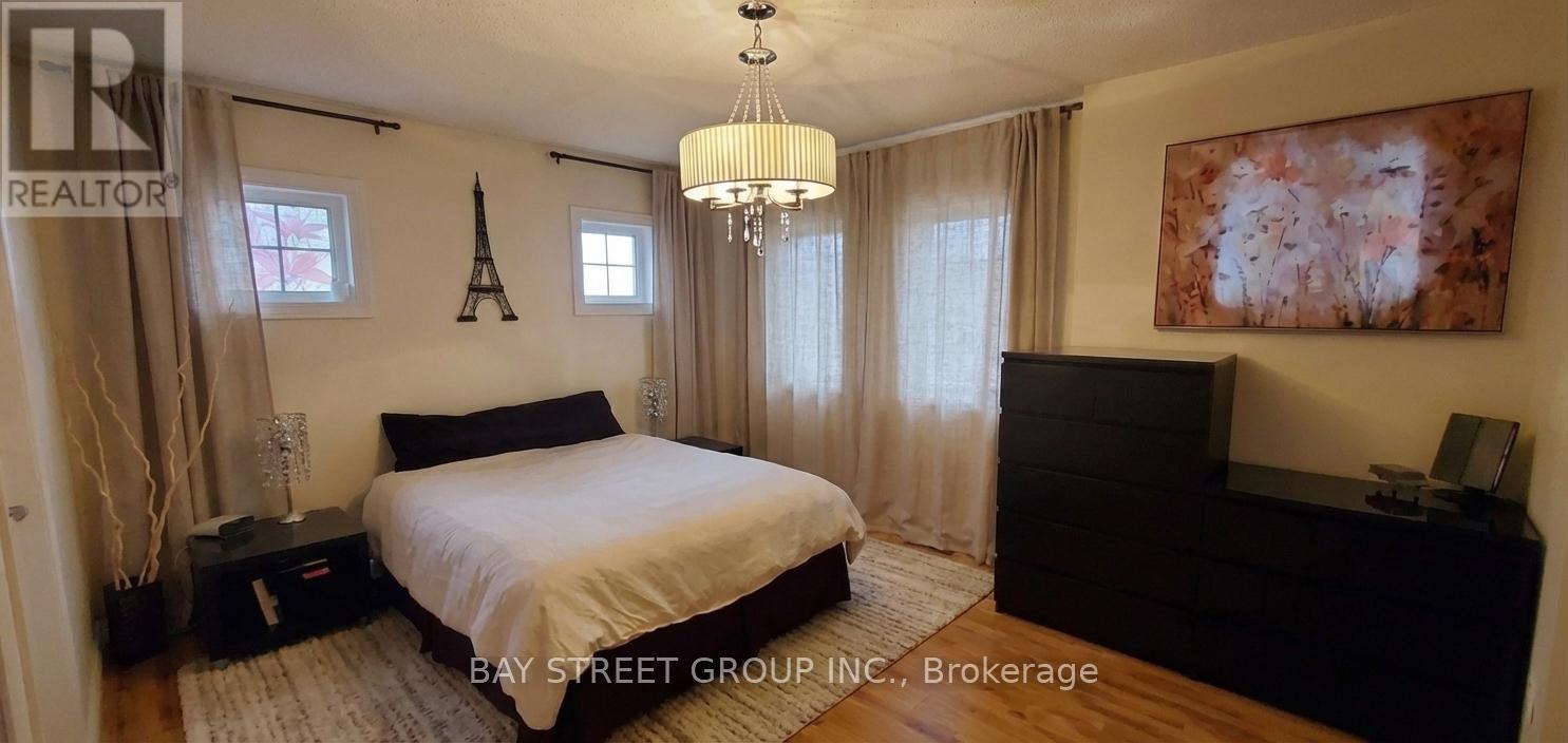 A bedroom with a large bed, a chandelier, and a painting on the wall.