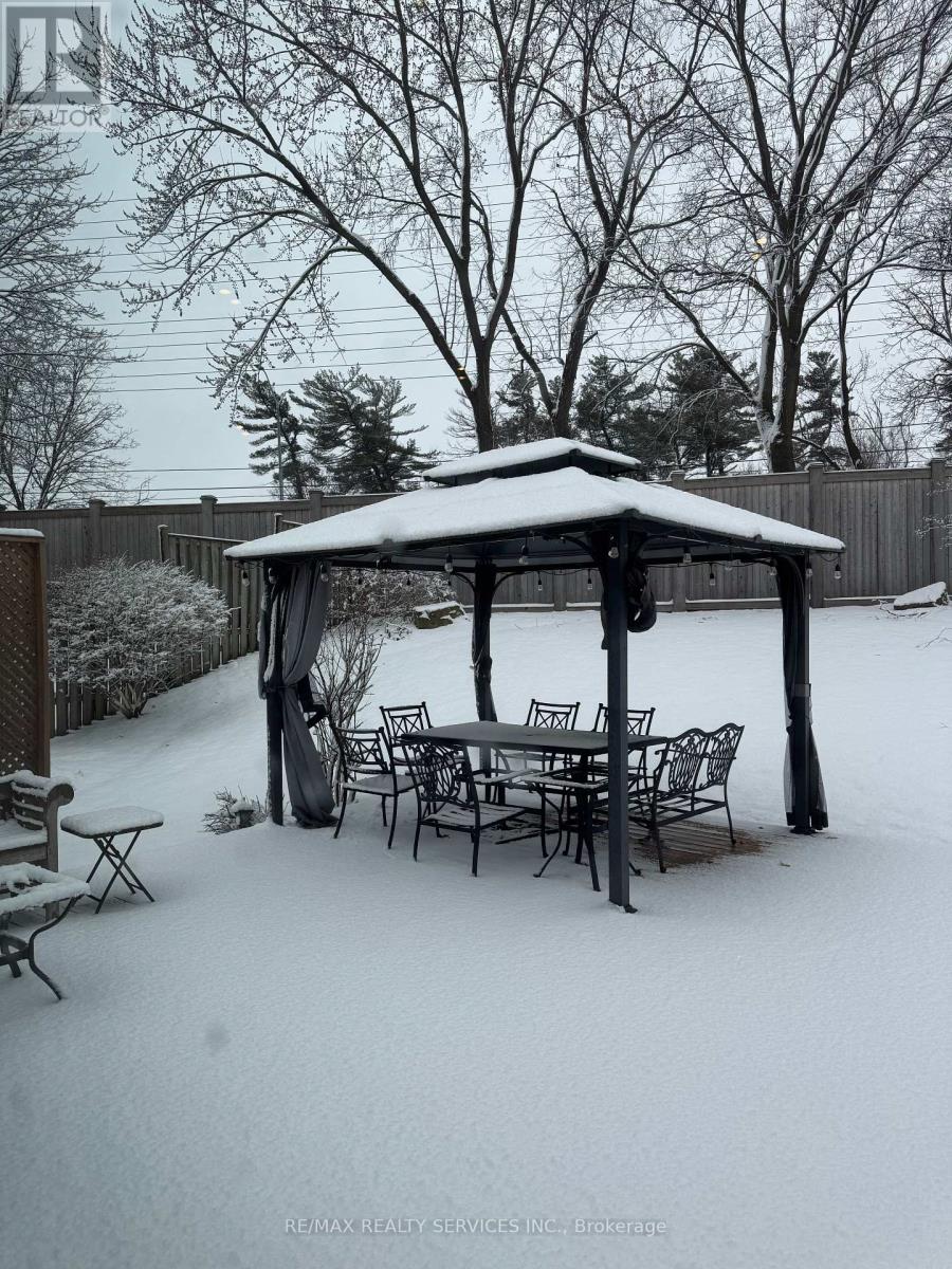 A gazebo covered in snow with a table and chairs around it.