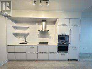 A white kitchen with a Realty One logo on the cabinet.