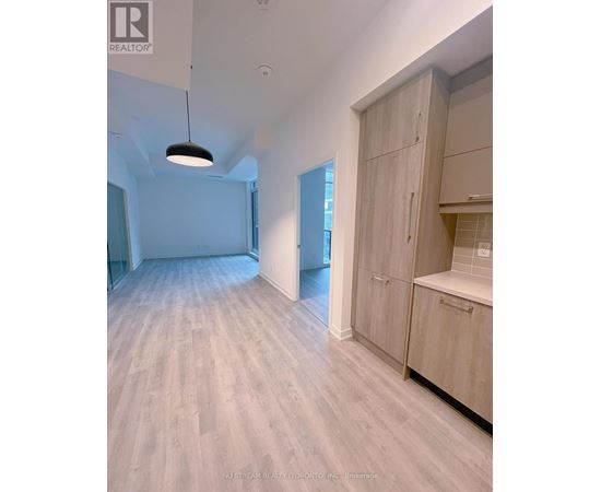 A spacious room with wooden flooring and a large open door.