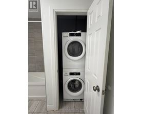 A white door opens to a small laundry room with a washer and dryer.