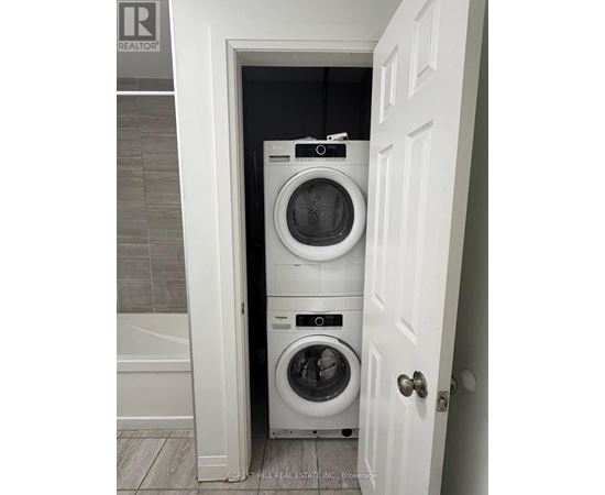 A white door opens to a small laundry room with a washer and dryer.