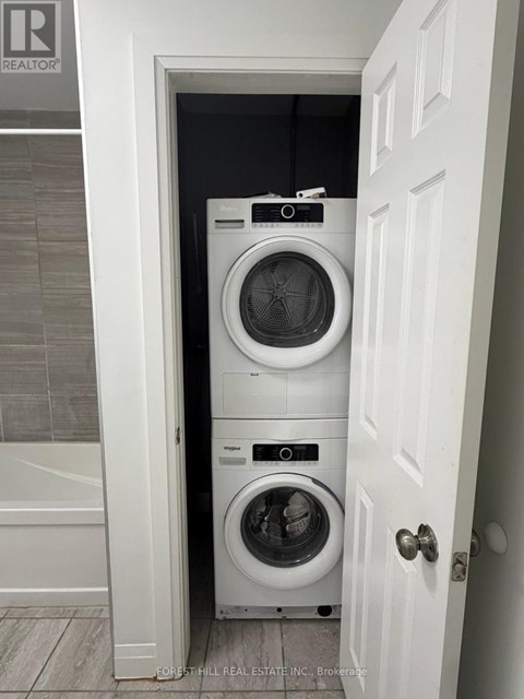 A white door opens to a small laundry room with a washer and dryer.