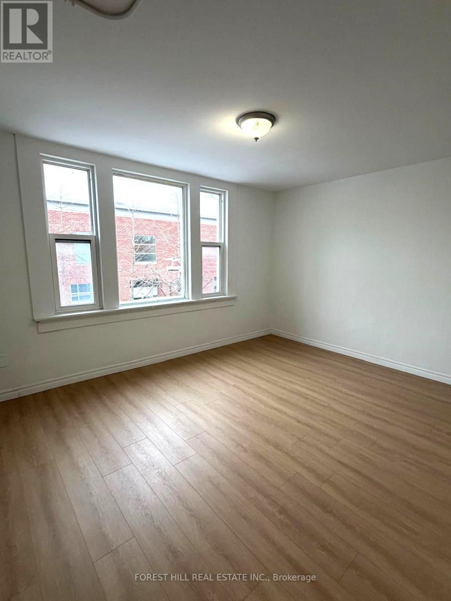 A room with wooden flooring and two windows.