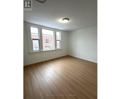 A room with wooden flooring and two windows.