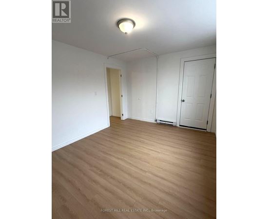 A room with wooden flooring and white walls.