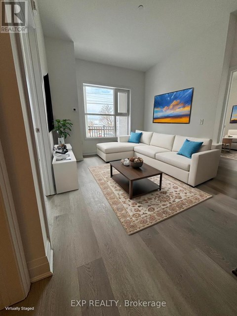 A living room with a white couch and a painting on the wall.