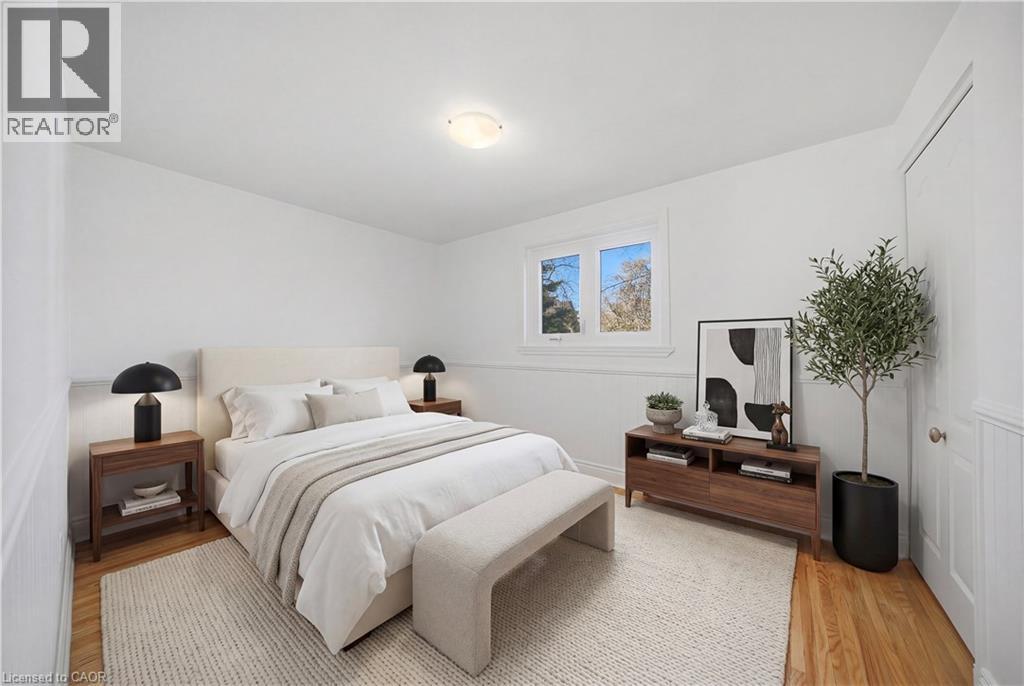 A bedroom with a large bed, a nightstand with a lamp, and a small tree.