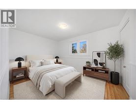 A bedroom with a large bed, a nightstand with a lamp, and a small tree.