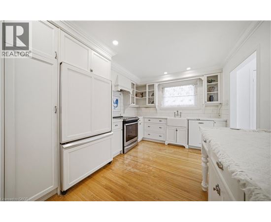A white kitchen with wooden floors and a refrigerator.