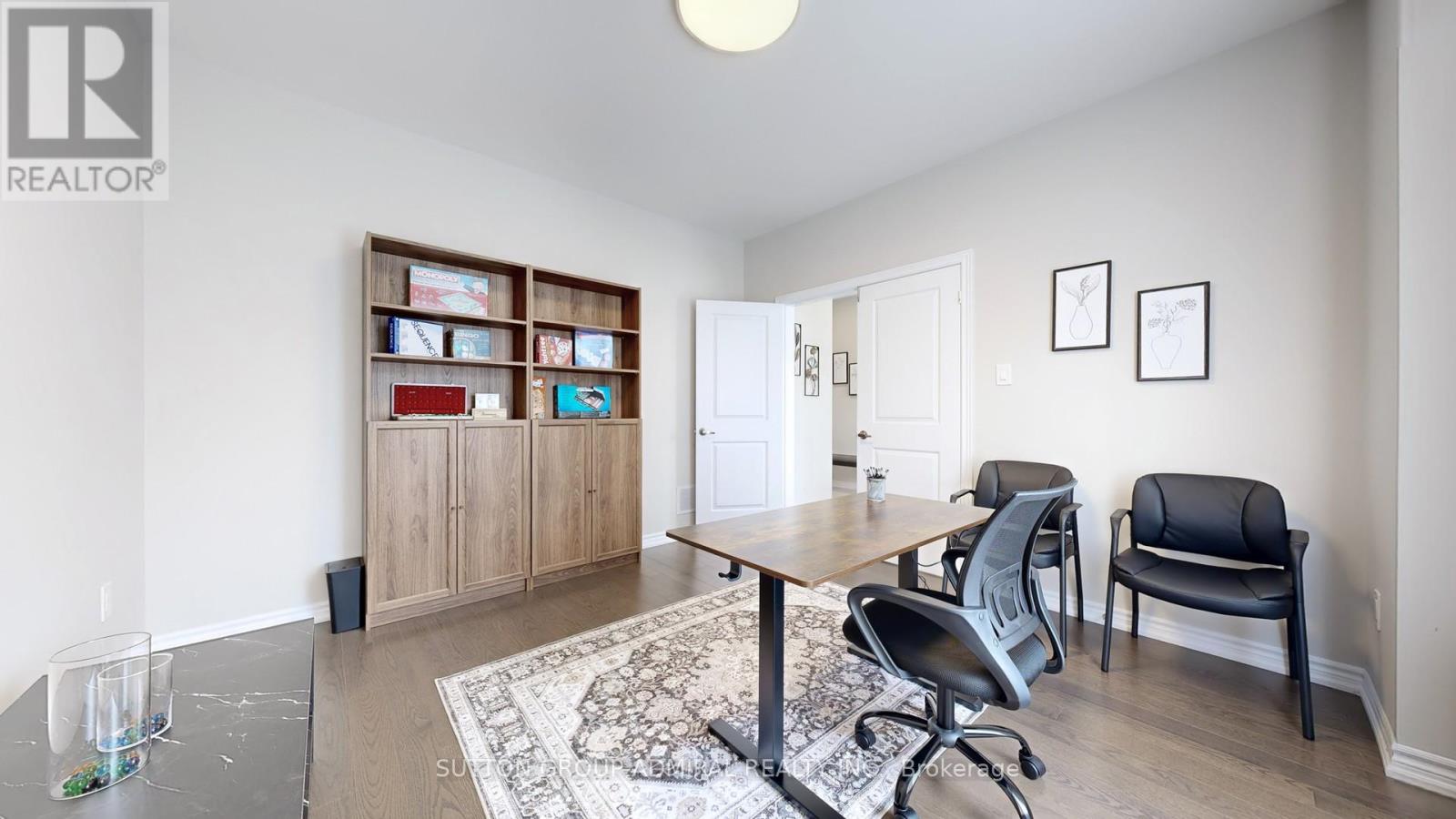 A spacious room with a dining table and chairs, a staircase, and a painting on the wall.