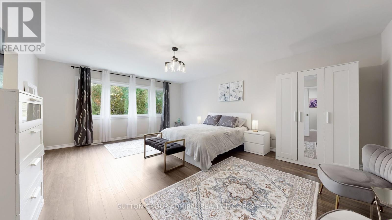 A well-lit bedroom with a large bed and a television.