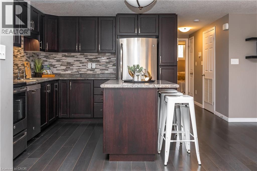 A kitchen with dark wood cabinets and a stainless steel refrigerator.