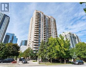 A tall residential building is surrounded by trees and other buildings.
