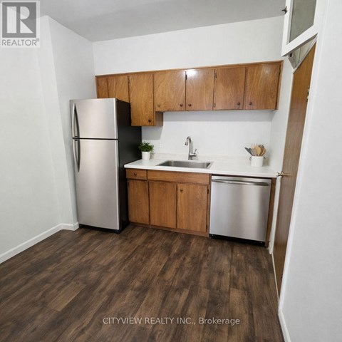 A kitchen with a refrigerator, sink, and cabinets.