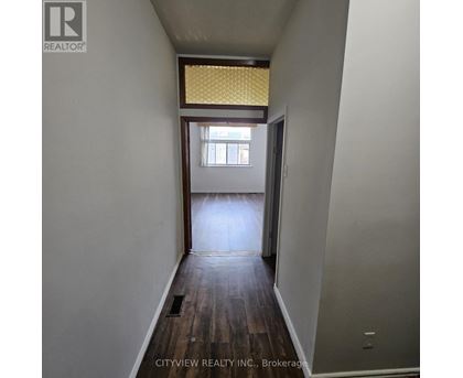 A hallway with wood floors and a window with yellow blinds.