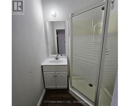 A white bathroom with a sink, mirror, and shower.